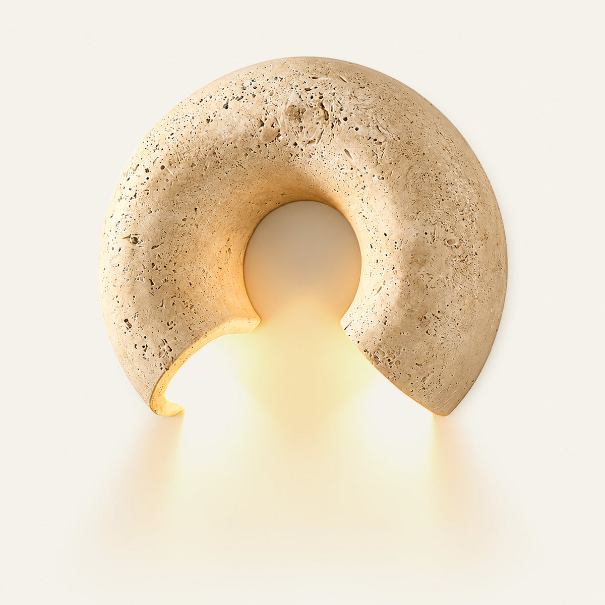 The Arco travertine wall light, a stone arch, lit