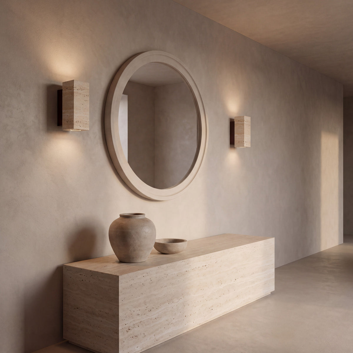A pair of Blocco travertine wall lights either side of a mirror above a travertine console