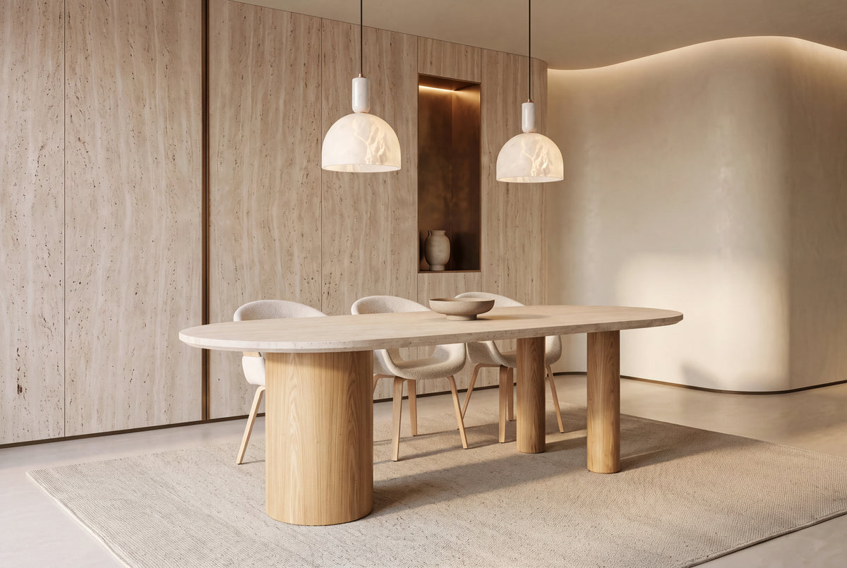 The Bracciano Oval Dining Table in cream beneath two alabaster pendants in a travertine-panelled dining room