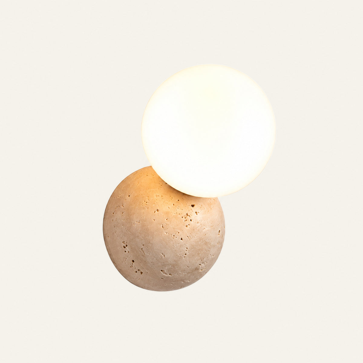 The Ciottolo travertine wall light, a stone pebble beside an opal glass globe