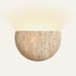 The Conchiglia travertine wall light, a half bowl of stone with light rising above