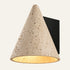 The Cuspide travertine wall light, a stone cone on a black wall plate