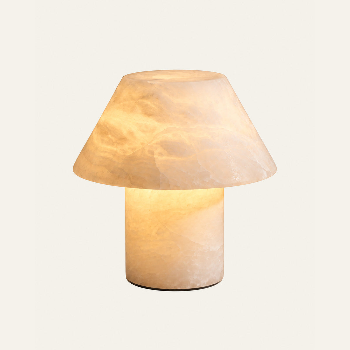The Fungo alabaster table lamp lit, with a stone shade on a stone column