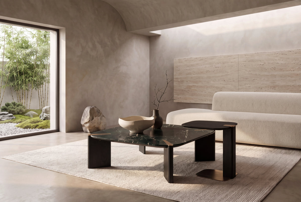 The Gaeta Marble Coffee Table Set in green marble, black oak and brass in a vaulted plaster room with a travertine slab