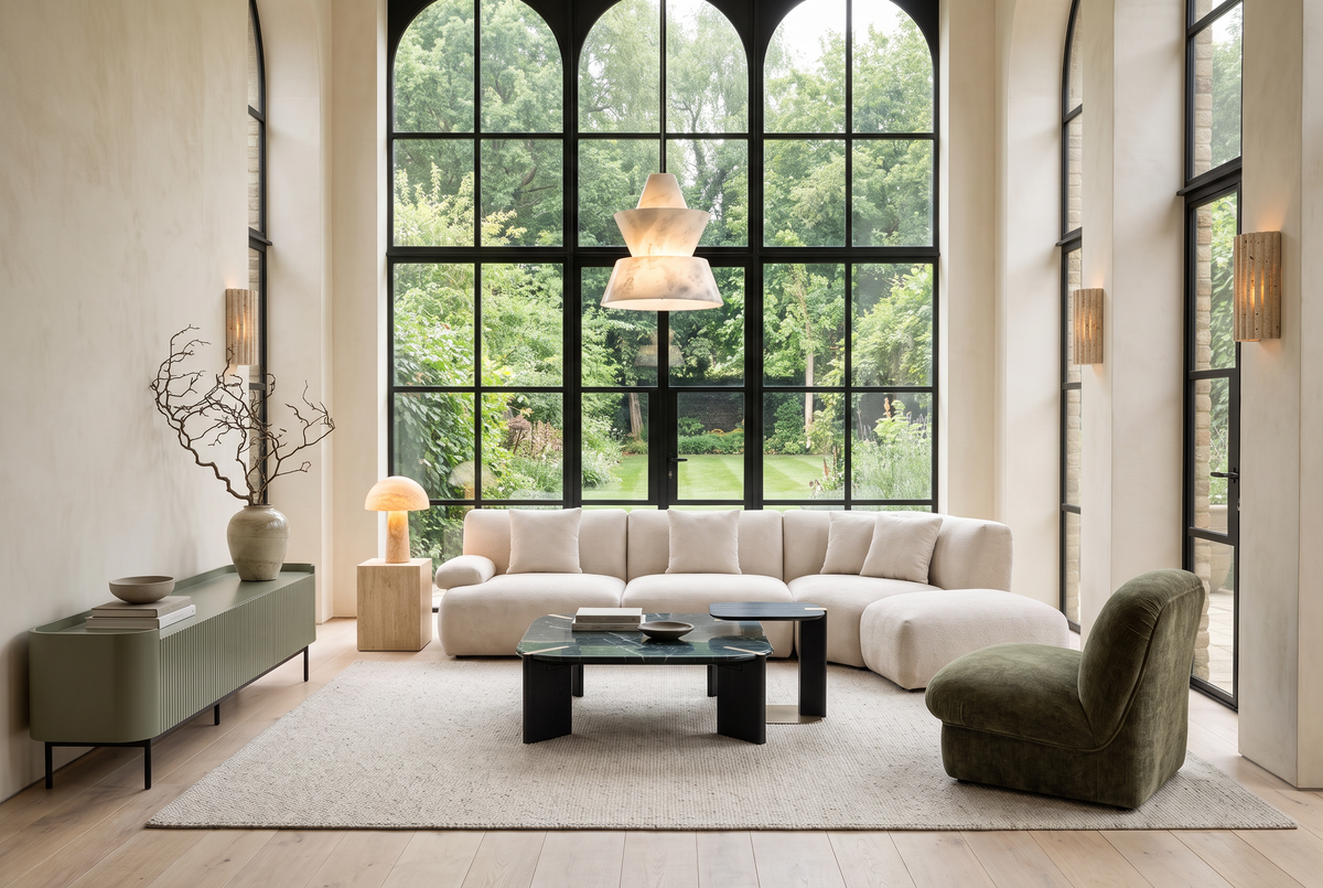 Verdant, a cream modular sofa, olive chair and green marble tables beneath tall arched garden windows