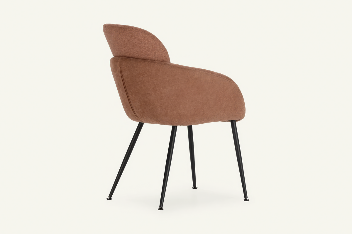 The Arona Armchair in coral, upholstered tub armchair on slim black legs, studio view