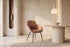 The Arona Armchair in coral, upholstered tub armchair on slim black legs, styled in a room