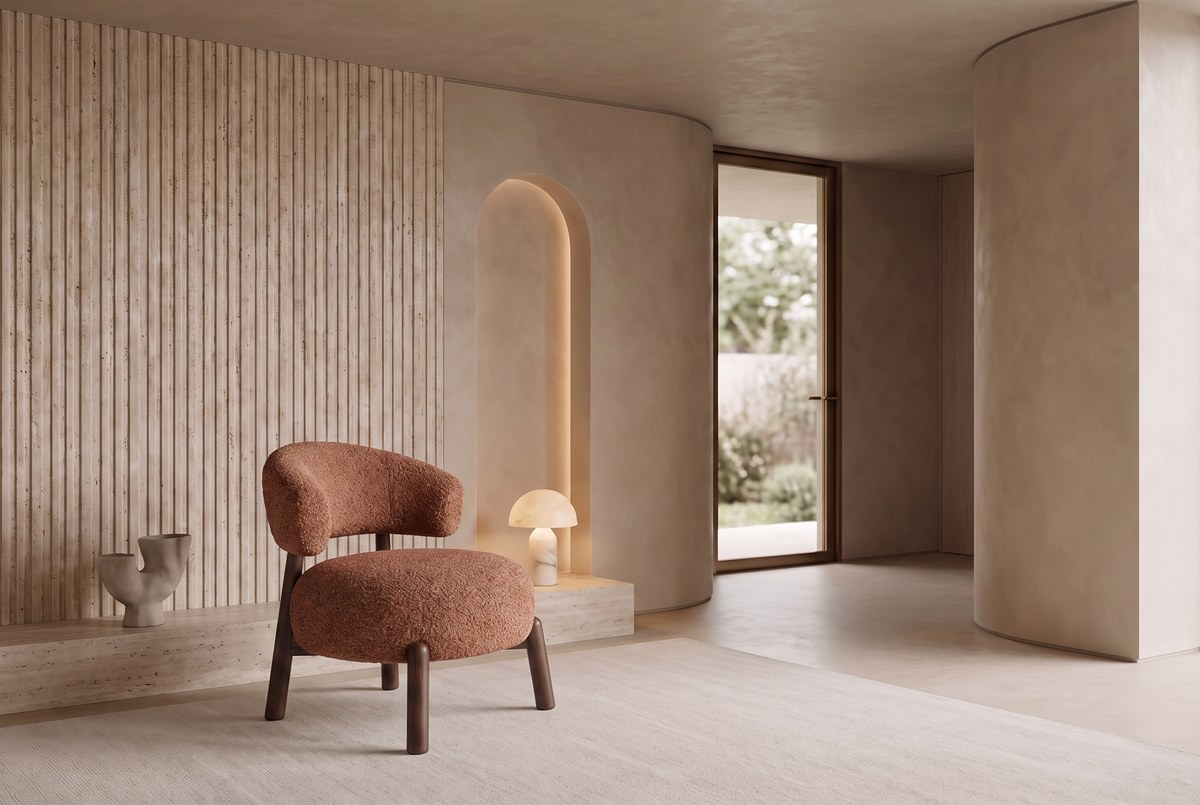 The Bardolino Armchair in terracotta boucle beside a fluted travertine wall and lit arched niche