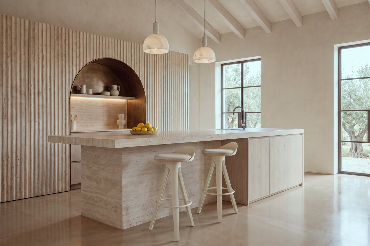 Two Bonassola Counter Stools in beige at a travertine kitchen island in a beamed kitchen with olive trees beyond