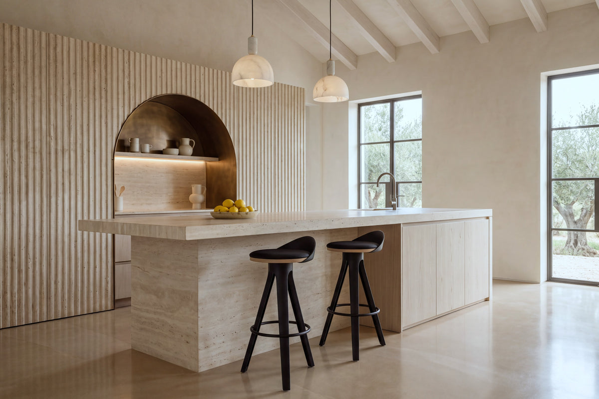 Two Bonassola Counter Stools in black at a travertine kitchen island in a beamed kitchen with olive trees beyond