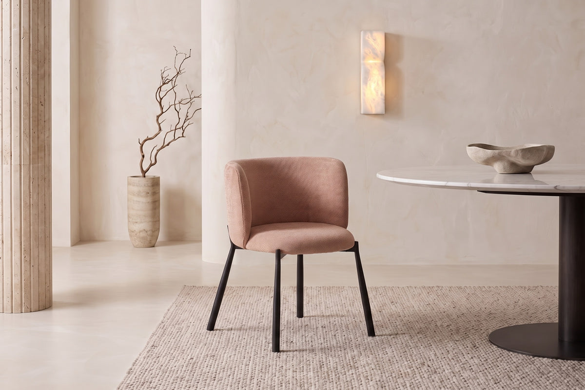 The Bormio Dining Armchair in coral, upholstered dining armchair on black metal legs, styled in a room