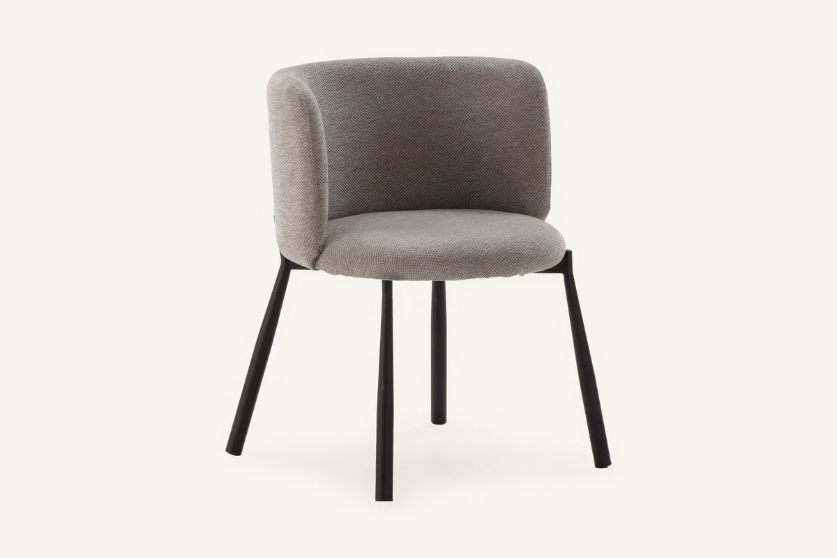 The Bormio Dining Armchair in grey, upholstered dining armchair on black metal legs, studio view