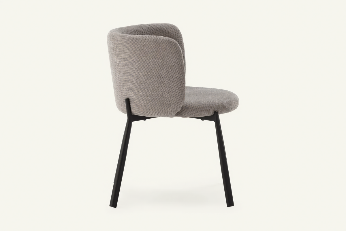 The Bormio Dining Armchair in grey, upholstered dining armchair on black metal legs, studio view
