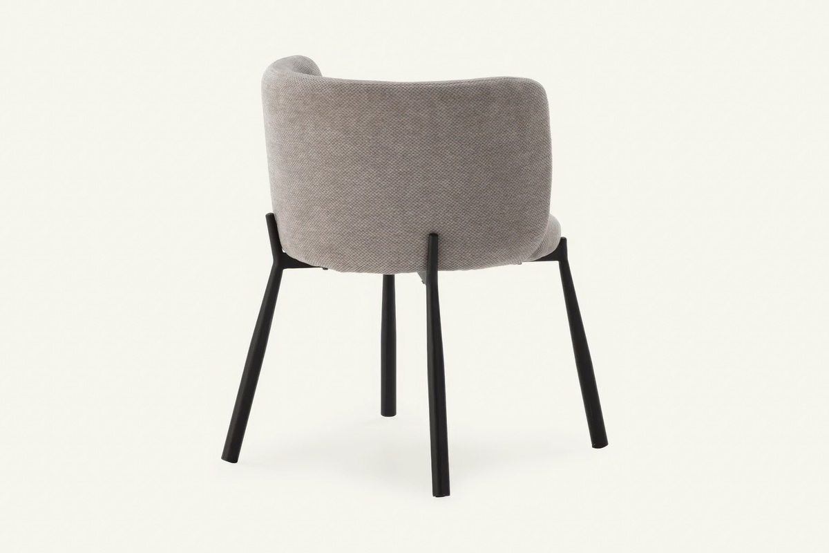 The Bormio Dining Armchair in grey, upholstered dining armchair on black metal legs, studio view