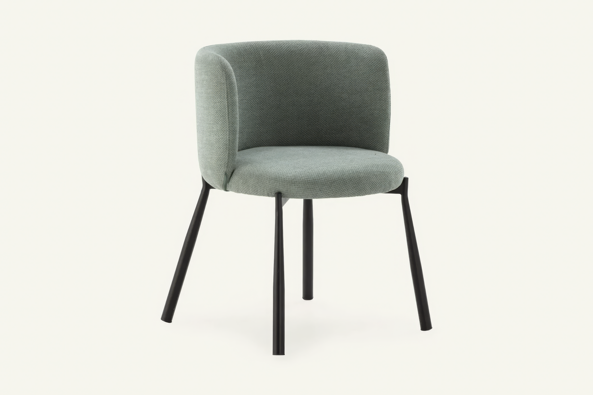 The Bormio Dining Armchair in sage, upholstered dining armchair on black metal legs, studio view