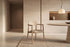 The Brescia Dining Armchair in beige and washed oak beside a travertine dining table beneath an alabaster pendant