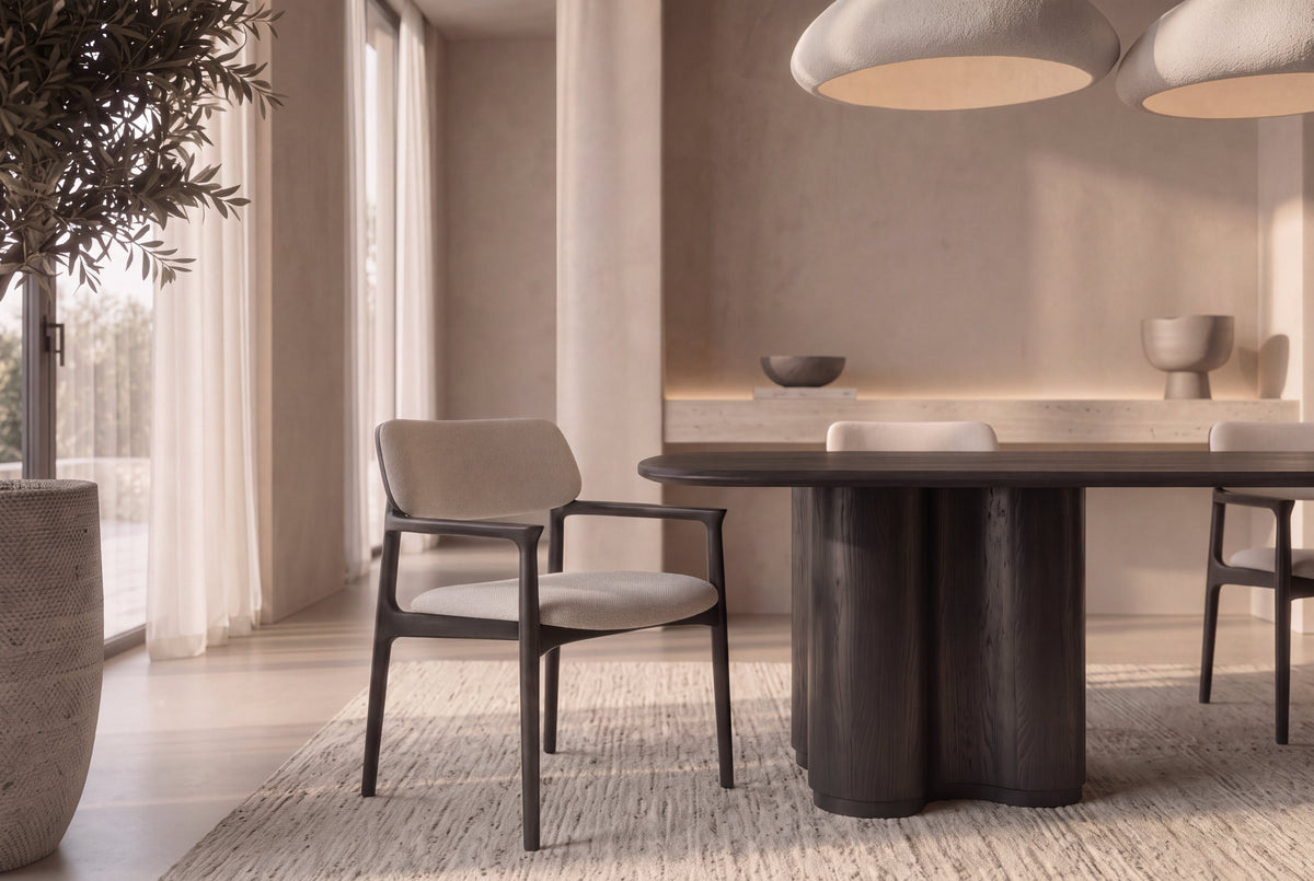 The Brindisi Dining Armchair with a black frame and ivory seat beside The Brindisi Dining Table in a plaster dining room