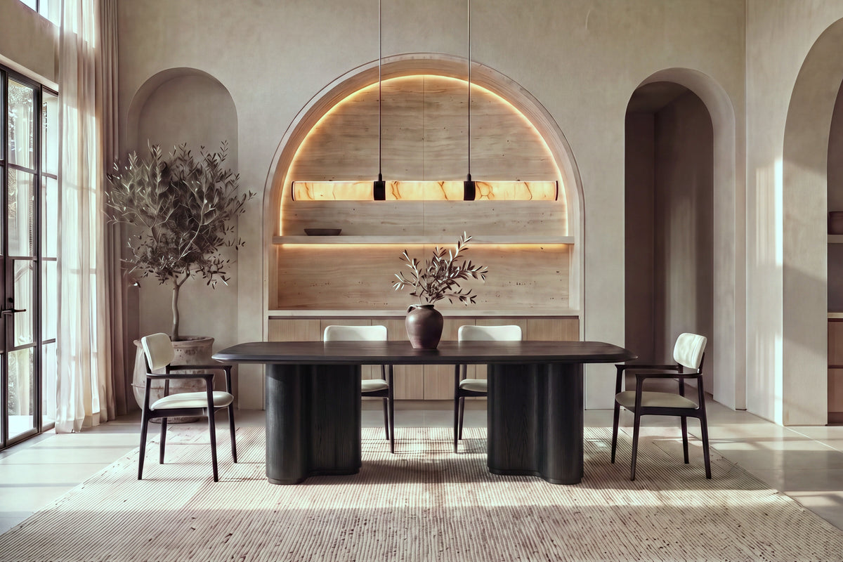 The Brindisi Dining Table in black oak with fluted wave pedestals and ivory dining armchairs in a plaster dining room