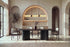 The Brindisi Dining Table in black oak with fluted wave pedestals and ivory dining armchairs in a plaster dining room