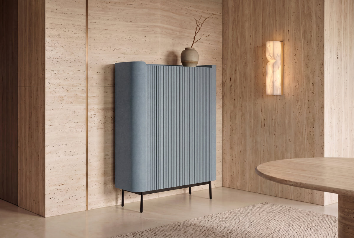 The Camogli Fluted Highboard in blue against a travertine wall beside an alabaster wall light