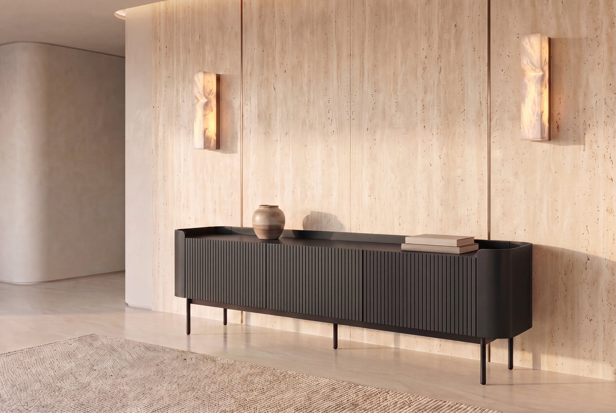 The Camogli Fluted TV Unit in black against a travertine wall between two alabaster wall lights