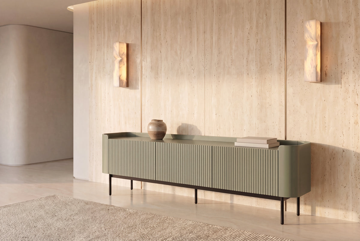 The Camogli Fluted TV Unit in sage against a travertine wall between two alabaster wall lights