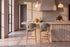 Two Cervo Counter Stools in green at a fluted travertine kitchen island beneath Cupola alabaster pendants