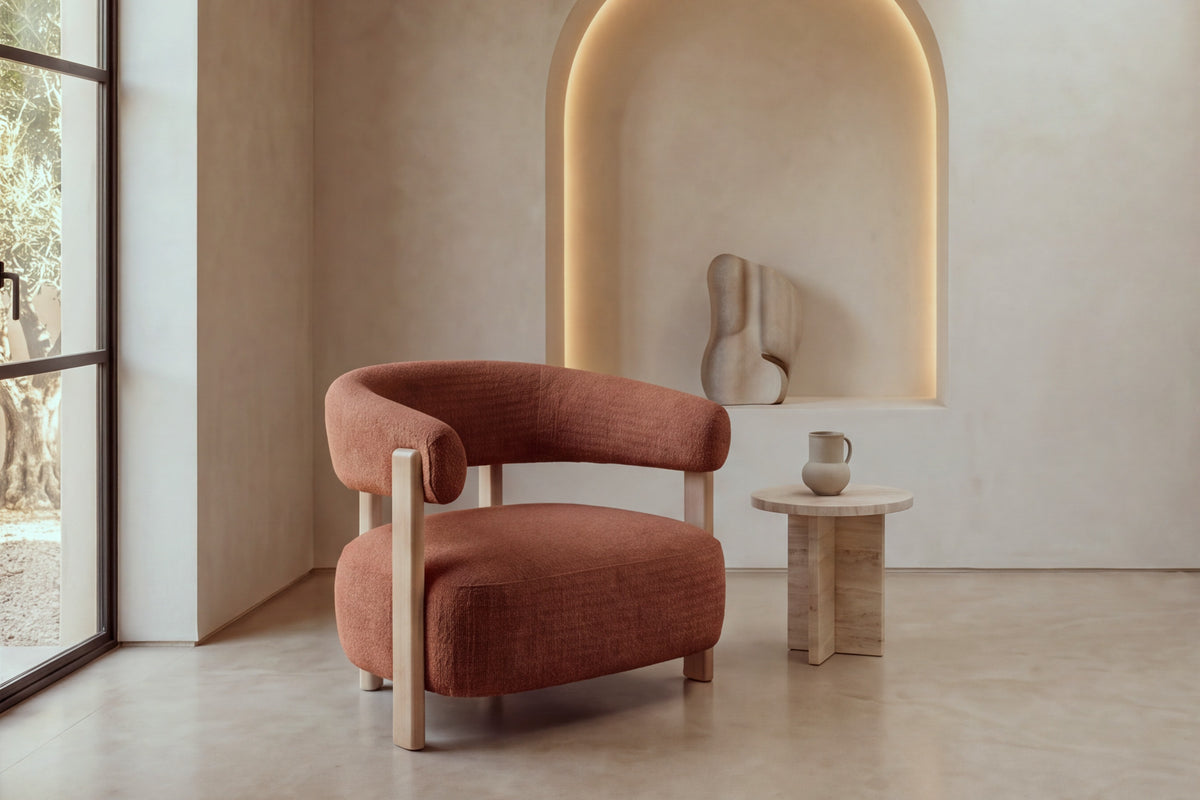 The Cetraro armchair in terracotta boucle beside a travertine side table