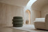 The Cisternino pouffe in green boucle on a wool rug in a vaulted travertine room