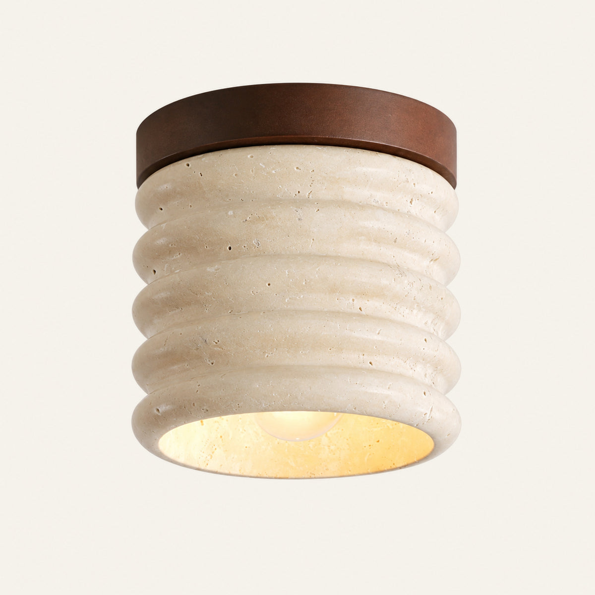 The Costa travertine flush ceiling light, a ribbed cream stone cylinder with a dark wood cap, lit from below