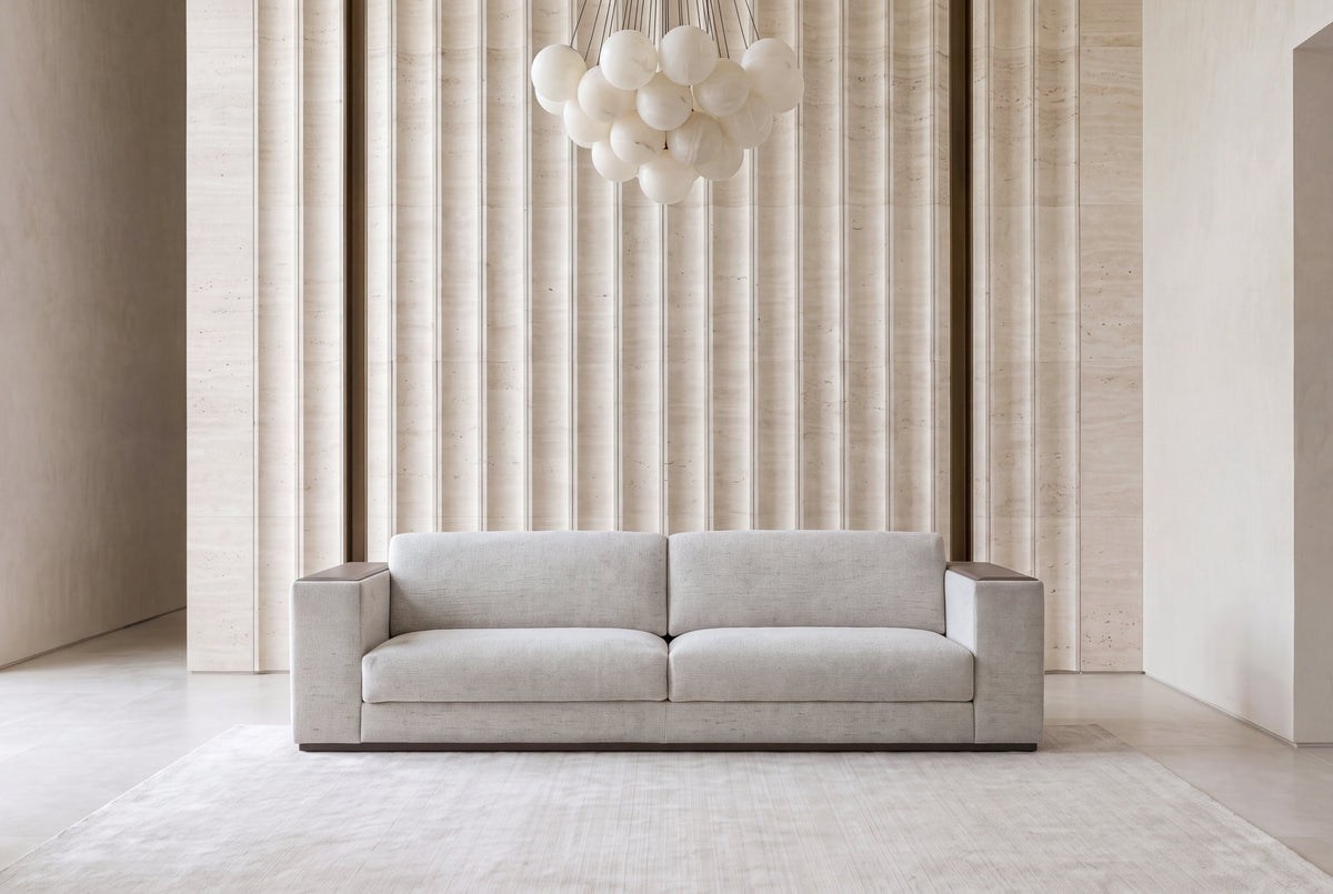 The Cremona Sofa in light grey weave, front view in a fluted travertine room