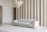 The Cremona Sofa in light grey weave with leather arm caps in a double-height room with a fluted travertine wall