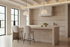 Two Deiva Counter Stools in beige at a travertine kitchen island beneath alabaster pendants