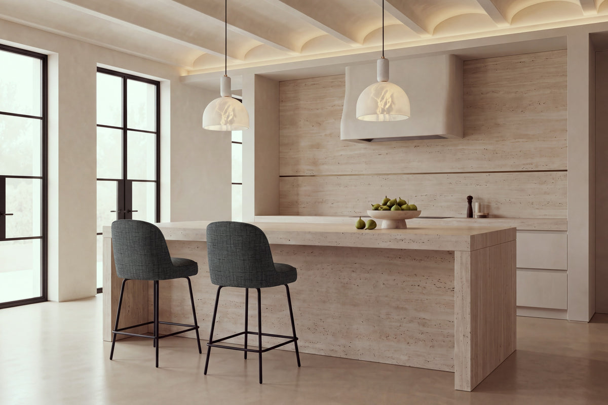 Two Deiva Counter Stools in dark grey at a travertine kitchen island beneath alabaster pendants