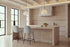 Two Deiva Counter Stools in light grey at a travertine kitchen island beneath alabaster pendants