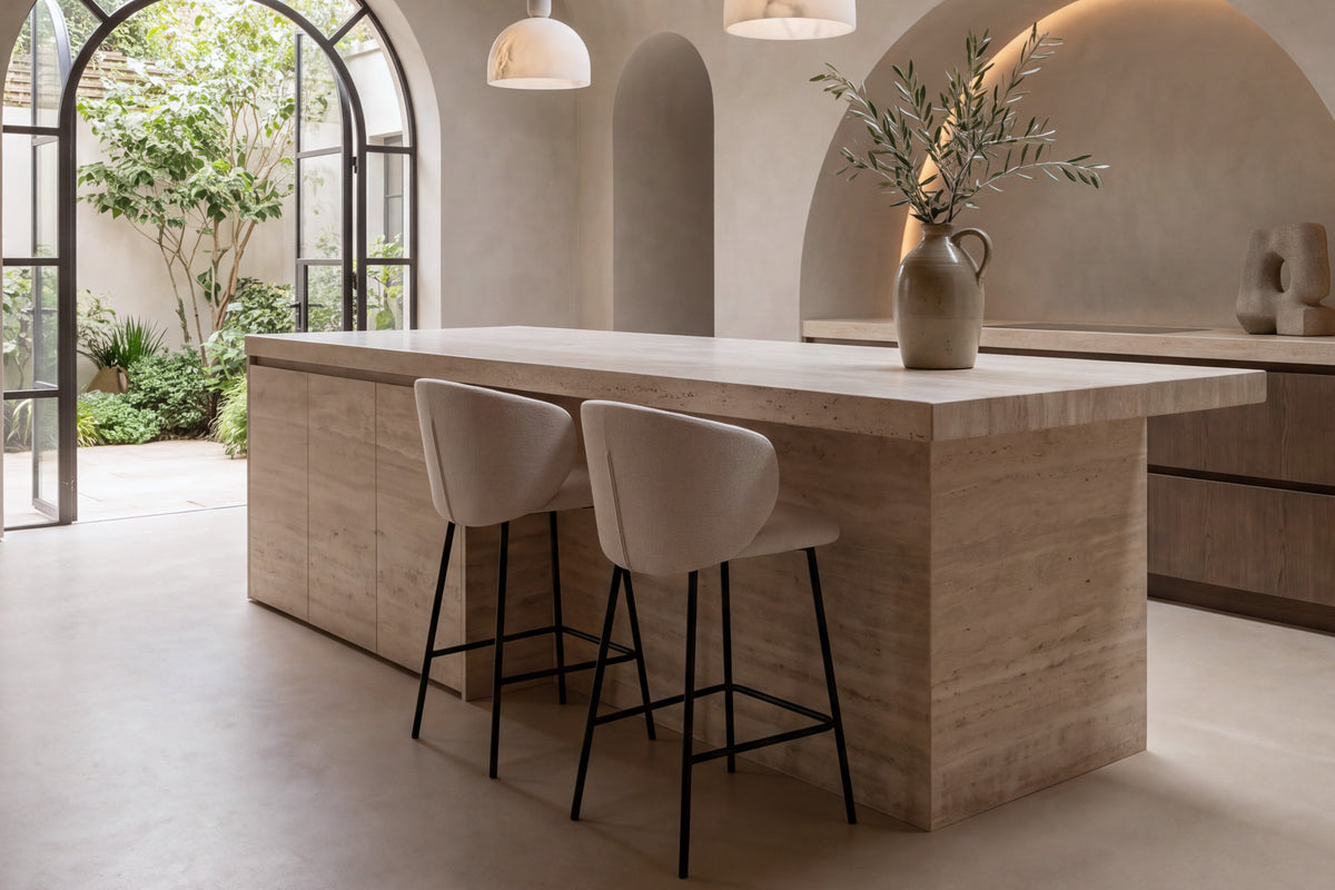 Two Framura Counter Stools in beige at a travertine kitchen island under a vaulted plaster ceiling
