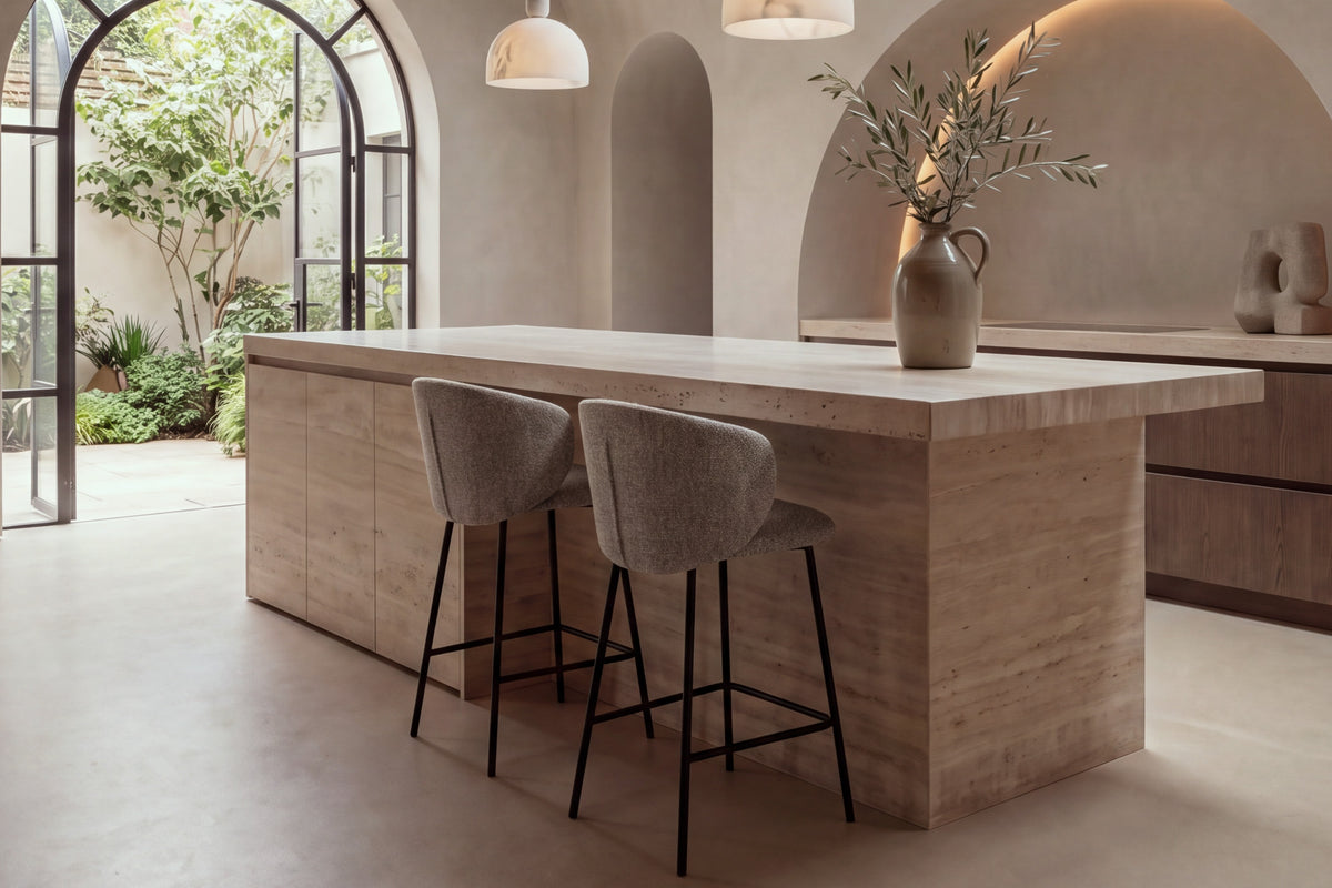 Two Framura Counter Stools in taupe at a travertine kitchen island under a vaulted plaster ceiling