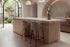 Two Framura Counter Stools in taupe at a travertine kitchen island under a vaulted plaster ceiling