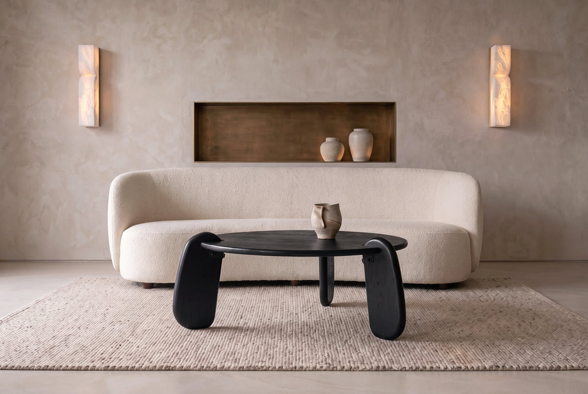 The Lipari Coffee Table in black, round mango wood coffee table with sculpted legs, styled in a room