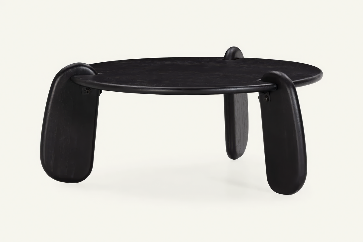 The Lipari Coffee Table in black, round mango wood coffee table with sculpted legs, studio view