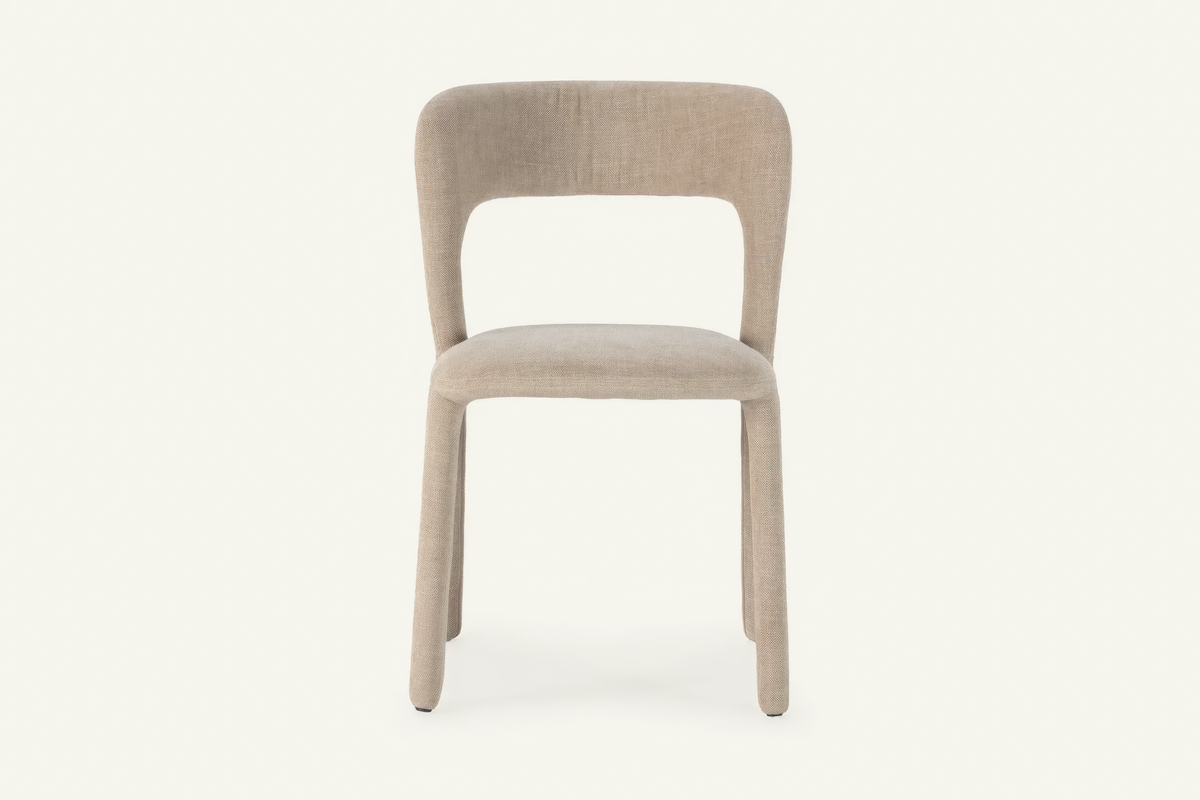 The Lucera Dining Chair in greige, sculptural upholstered dining chair with an open curved back, studio view