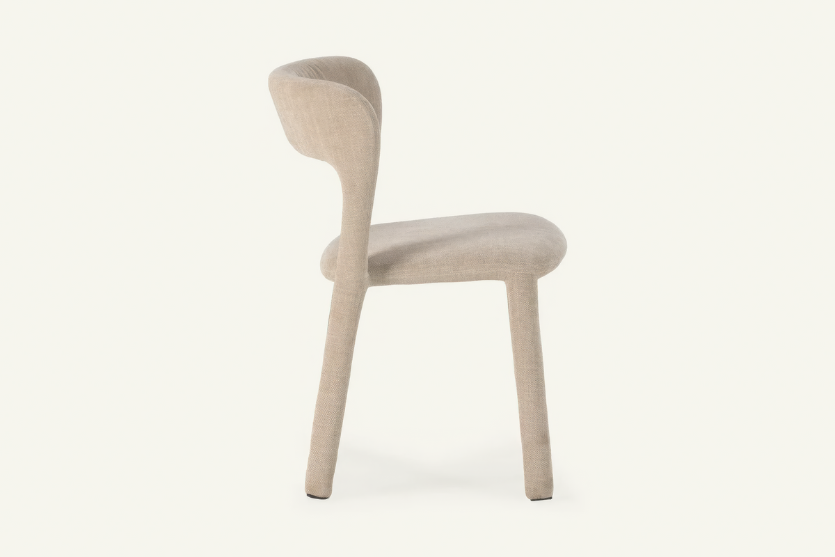 The Lucera Dining Chair in greige, sculptural upholstered dining chair with an open curved back, studio view