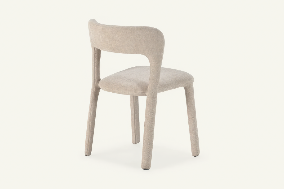 The Lucera Dining Chair in greige, sculptural upholstered dining chair with an open curved back, studio view