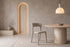The Lucera Dining Chair in greige, sculptural upholstered dining chair with an open curved back, styled in a room