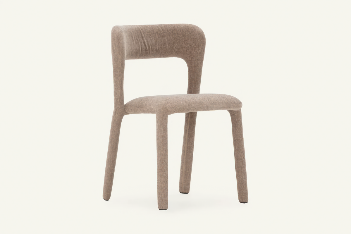 The Lucera Dining Chair in taupe, sculptural upholstered dining chair with an open curved back, studio view