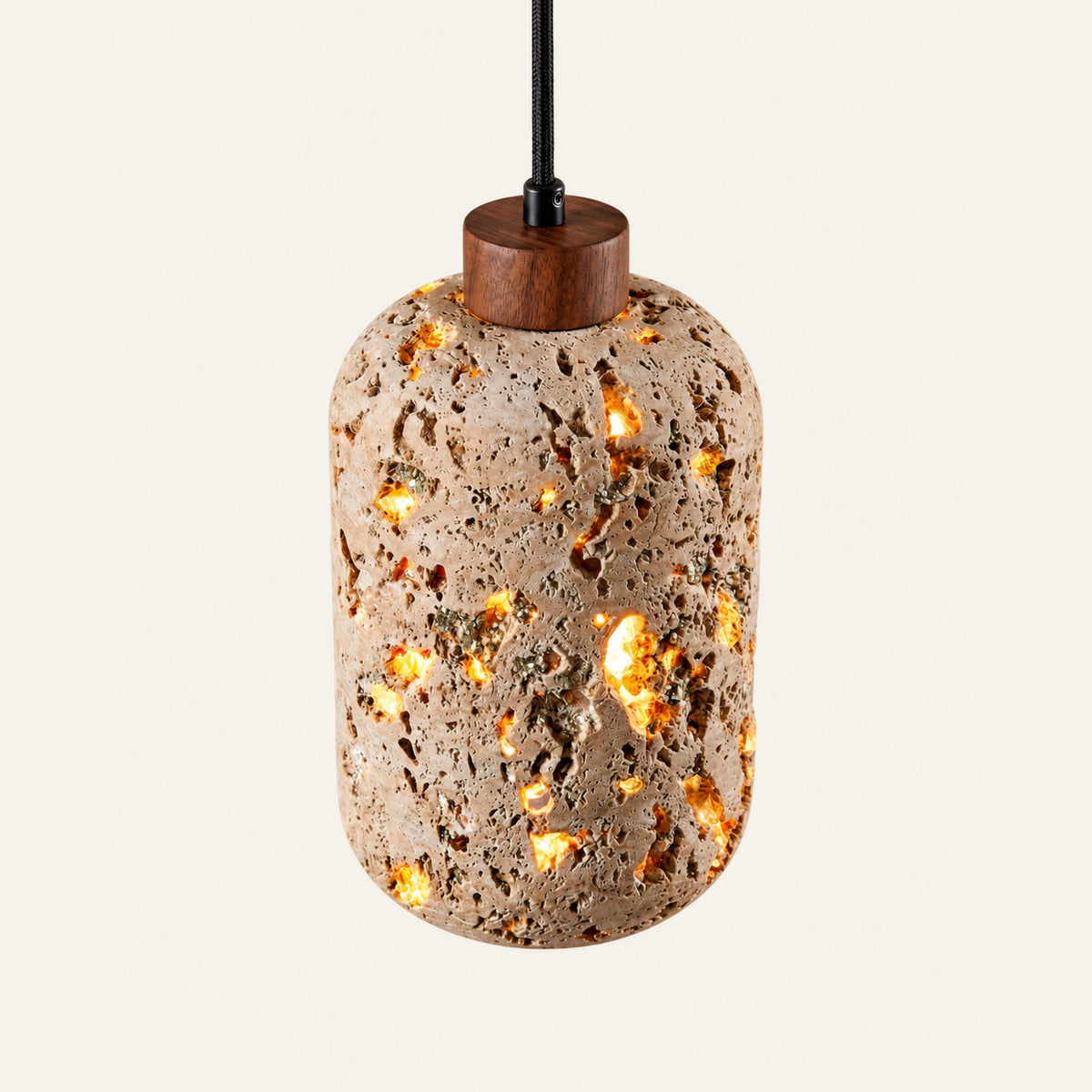 The Lumino travertine pendant light, a pierced travertine lantern with a wood cap, glowing through its pores