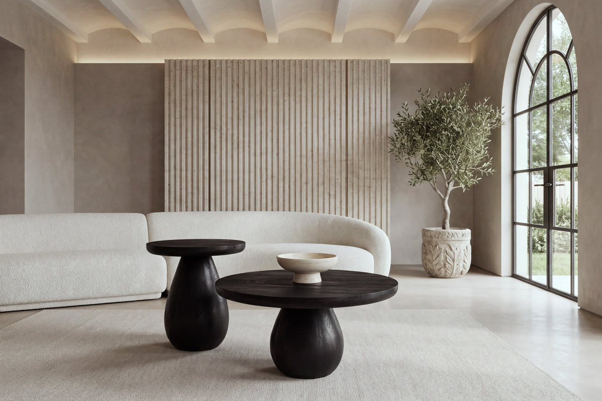 The Manarola Coffee Table Set in black mango wood in front of an ivory boucle sofa and a fluted travertine wall