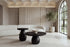 The Manarola Coffee Table Set in black mango wood in front of an ivory boucle sofa and a fluted travertine wall
