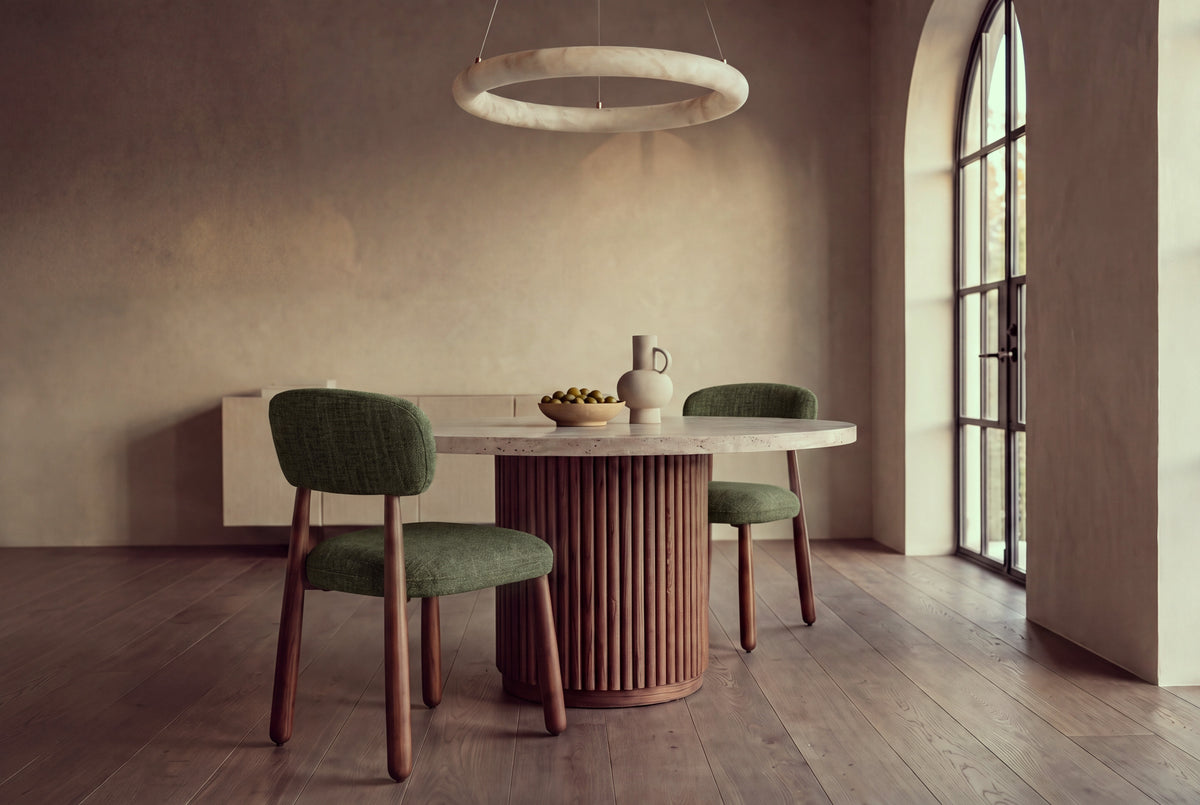 The Mantova Dining Chair in forest green and walnut at a round travertine dining table