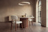 The Mantova Dining Chair in ivory and walnut at a round travertine dining table